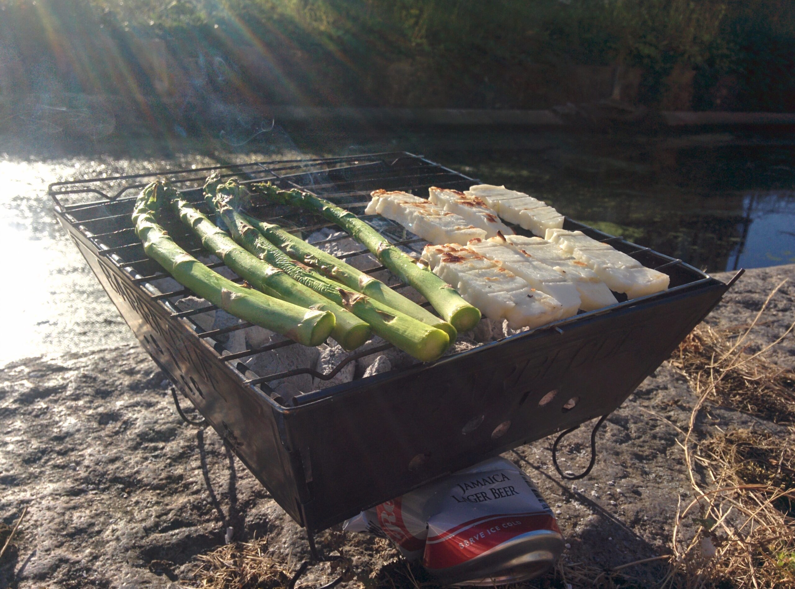 A photo of our BBQ by the canal in East End London. It is a sunny day. The BBQ is on the edge of the canal.